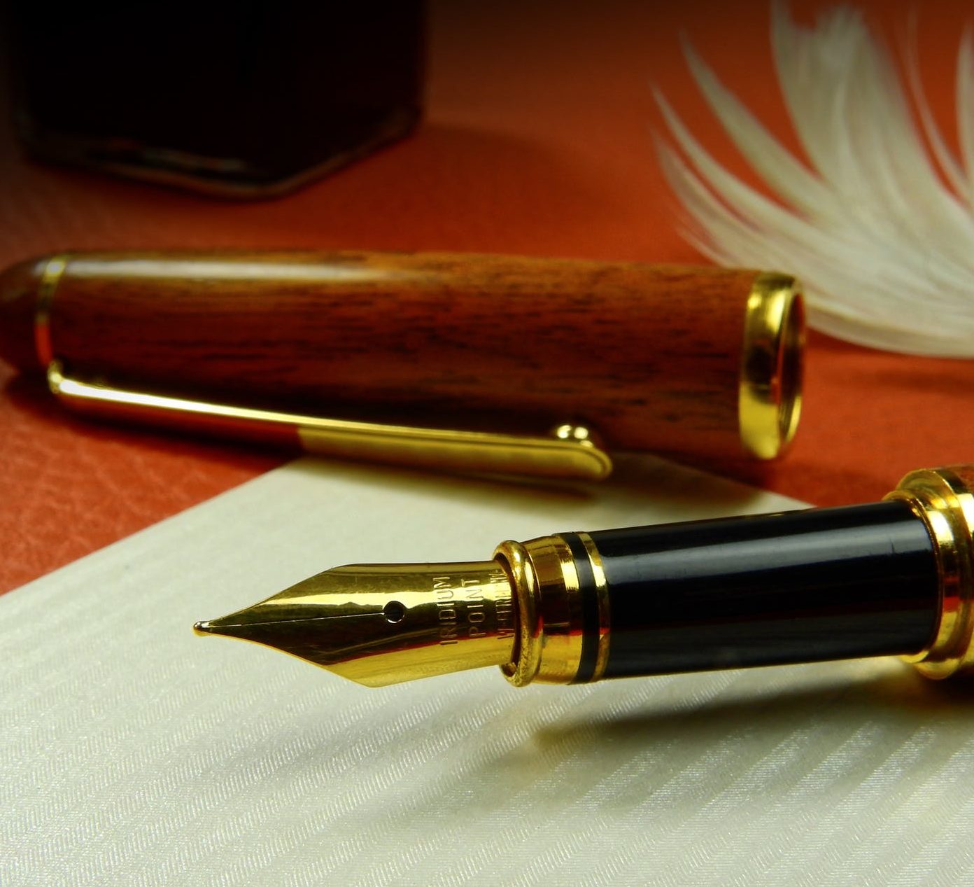 Opened fountain pen, focus on the nib with the cap in the background.